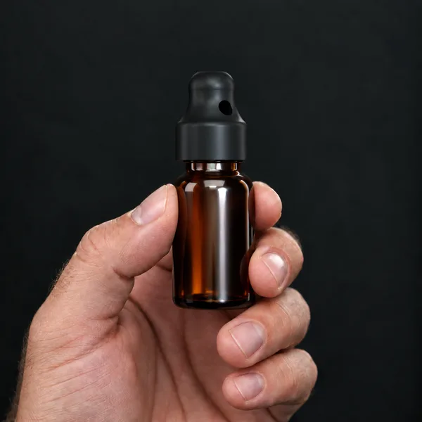 Main tenant un flacon 15 ml en verre ambré avec un bouchon sniffer SN*F Small