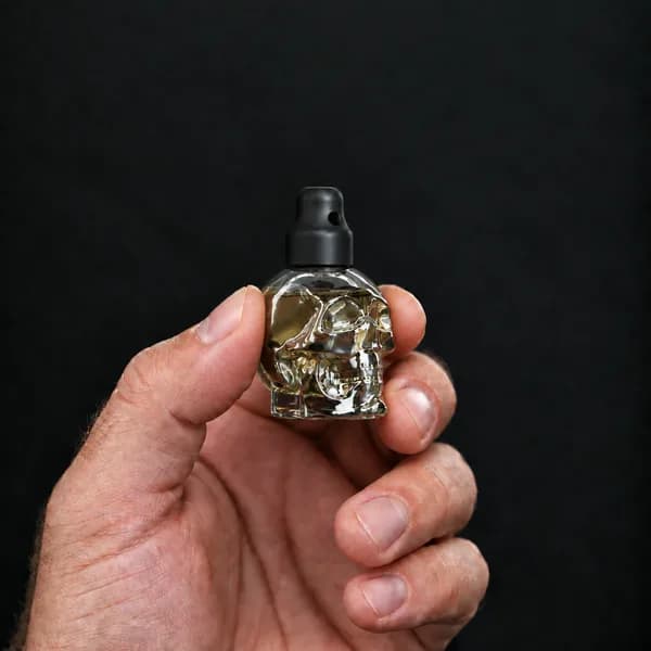 Main tenant un flacon 15 ml tête de mort, transparent avec un bouchon sniffer SN*F X-Small