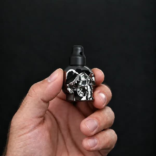 Main tenant un flacon 15 ml tête de mort, argenté avec un bouchon sniffer SN*F X-Small