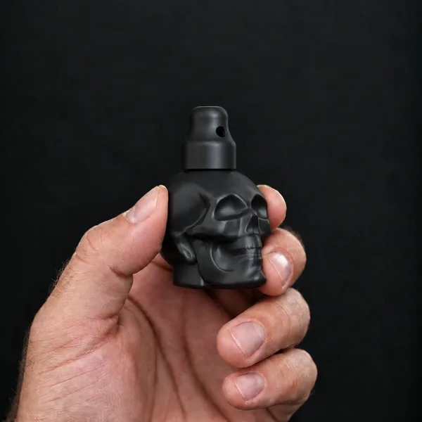 Main tenant un flacon 24 ml tête de mort, noir avec un bouchon sniffer SN*F X-Small