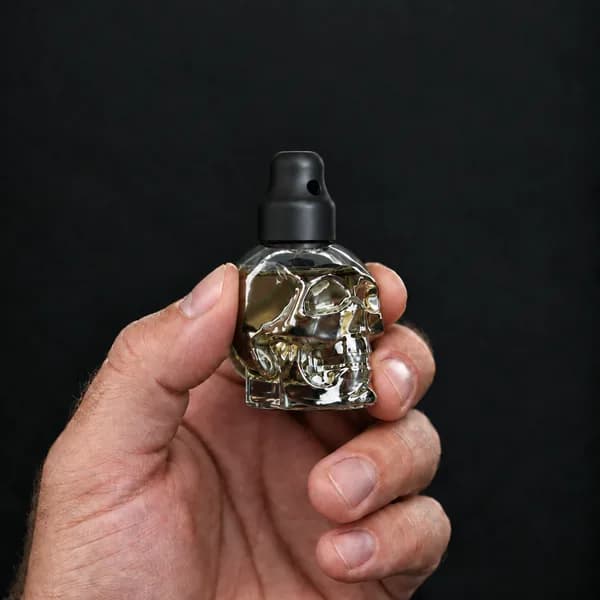 Main tenant un flacon 24 ml tête de mort, transparent avec un bouchon sniffer SN*F X-Small