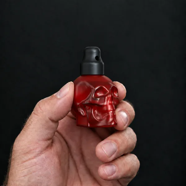 Main tenant un flacon 24 ml tête de mort, rouge avec un bouchon sniffer SN*F X-Small