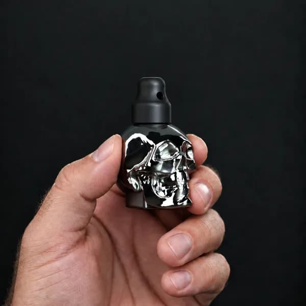 Main tenant un flacon 24 ml tête de mort, argenté avec un bouchon sniffer SN*F X-Small