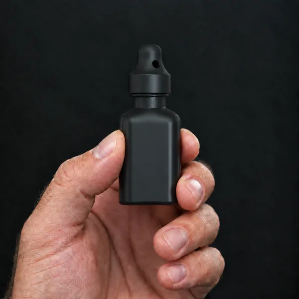 Main tenant un flacon 24 ml carré, noir avec un bouchon sniffer SN*F Large